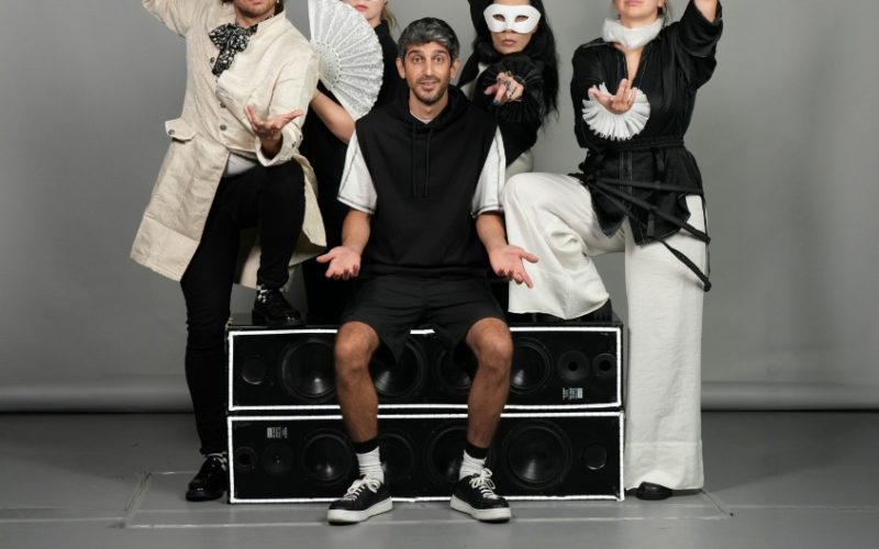From the show "Something Is Missing". An actor is sitting confused while around him four other actors (three women and a man) are dressed-up and posing with their hands in the air. They are wearing eye masks.