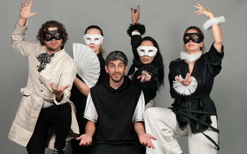 From the show "Something Is Missing". An actor is sitting confused while around him four other actors (three women and a man) are dressed-up and posing with their hands in the air. They are wearing eye masks.